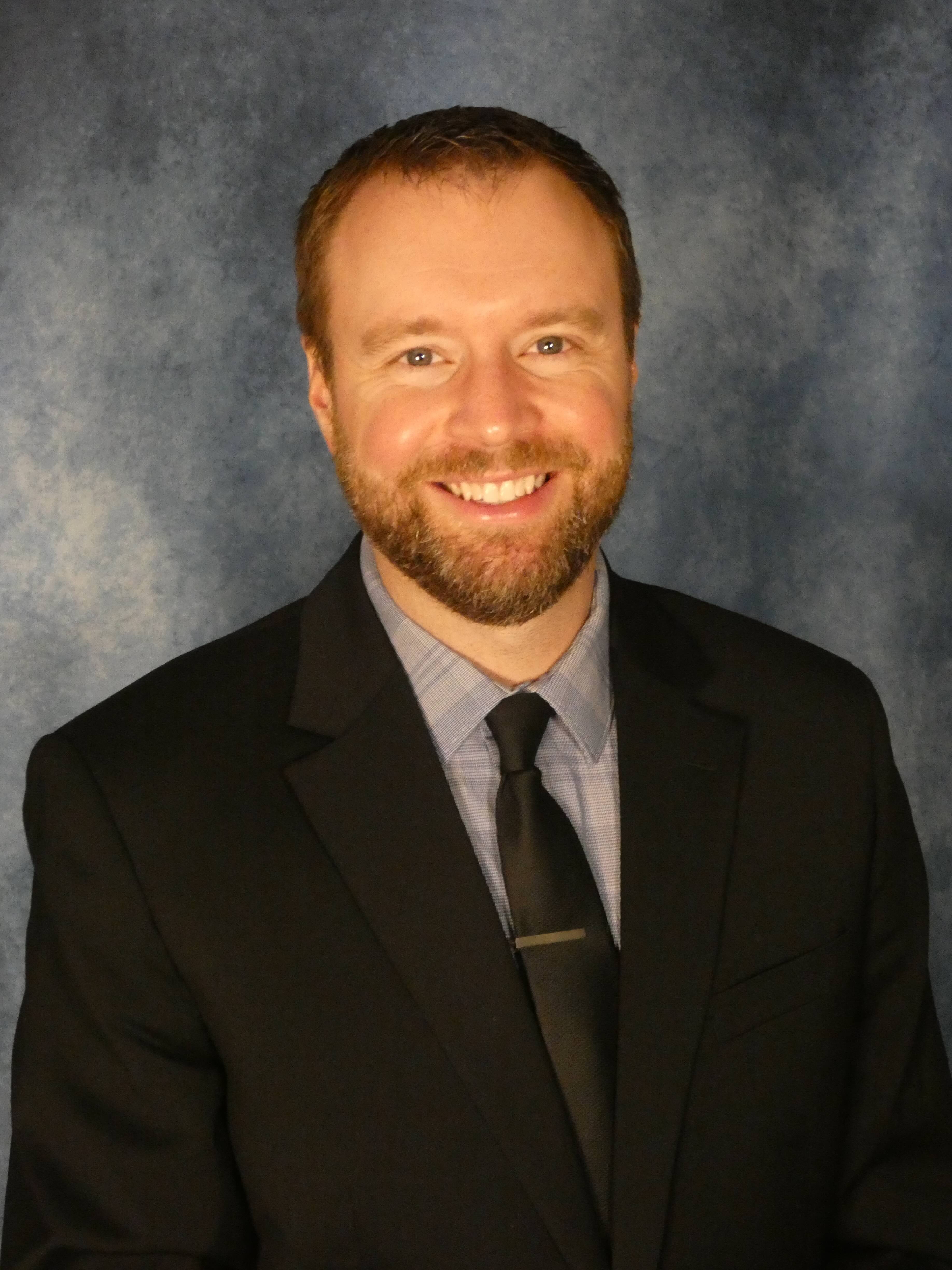 Studio headhot photo of man in black suit