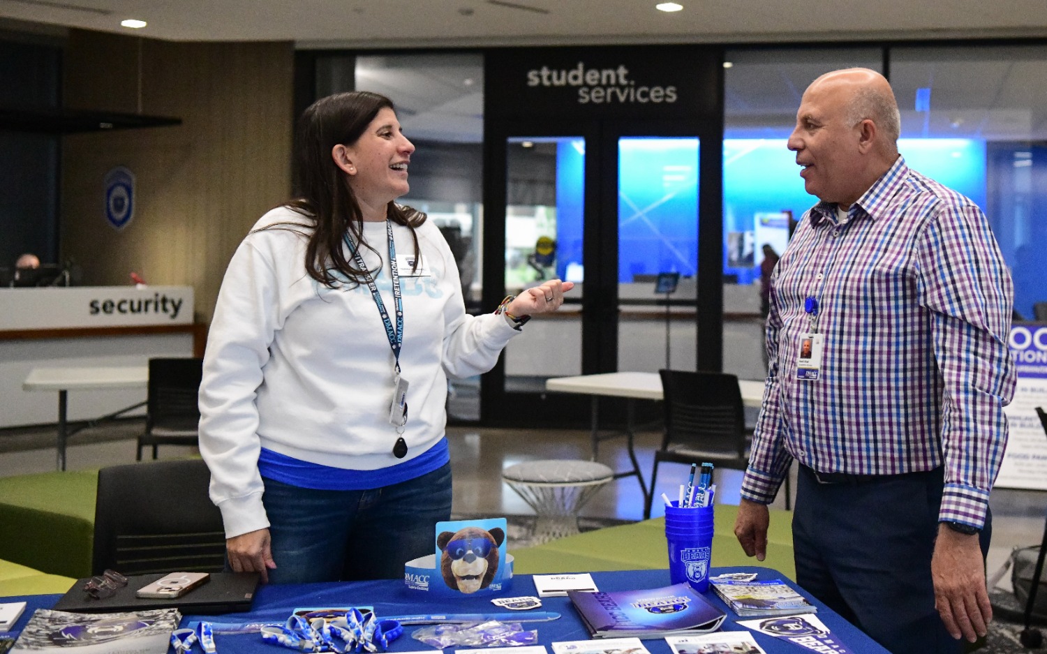 Two people stand at a table with promotional materials at an event