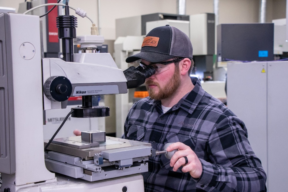 A man operates a microscope in the molding process at Accumold. 