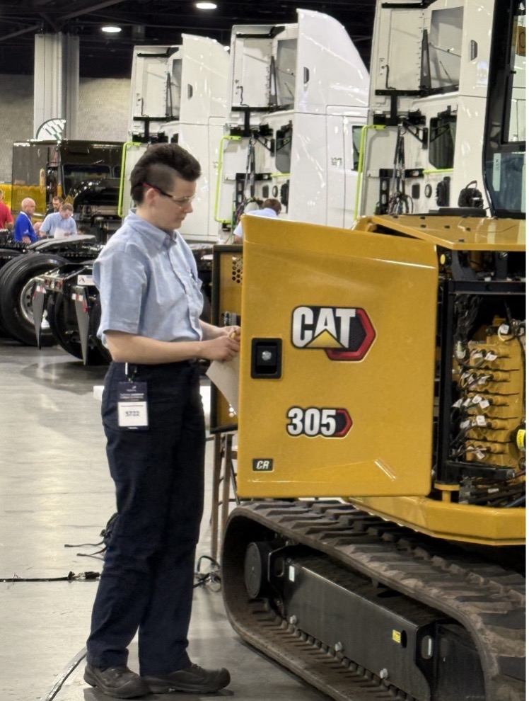 Student works on large yellow diesel machine during competition