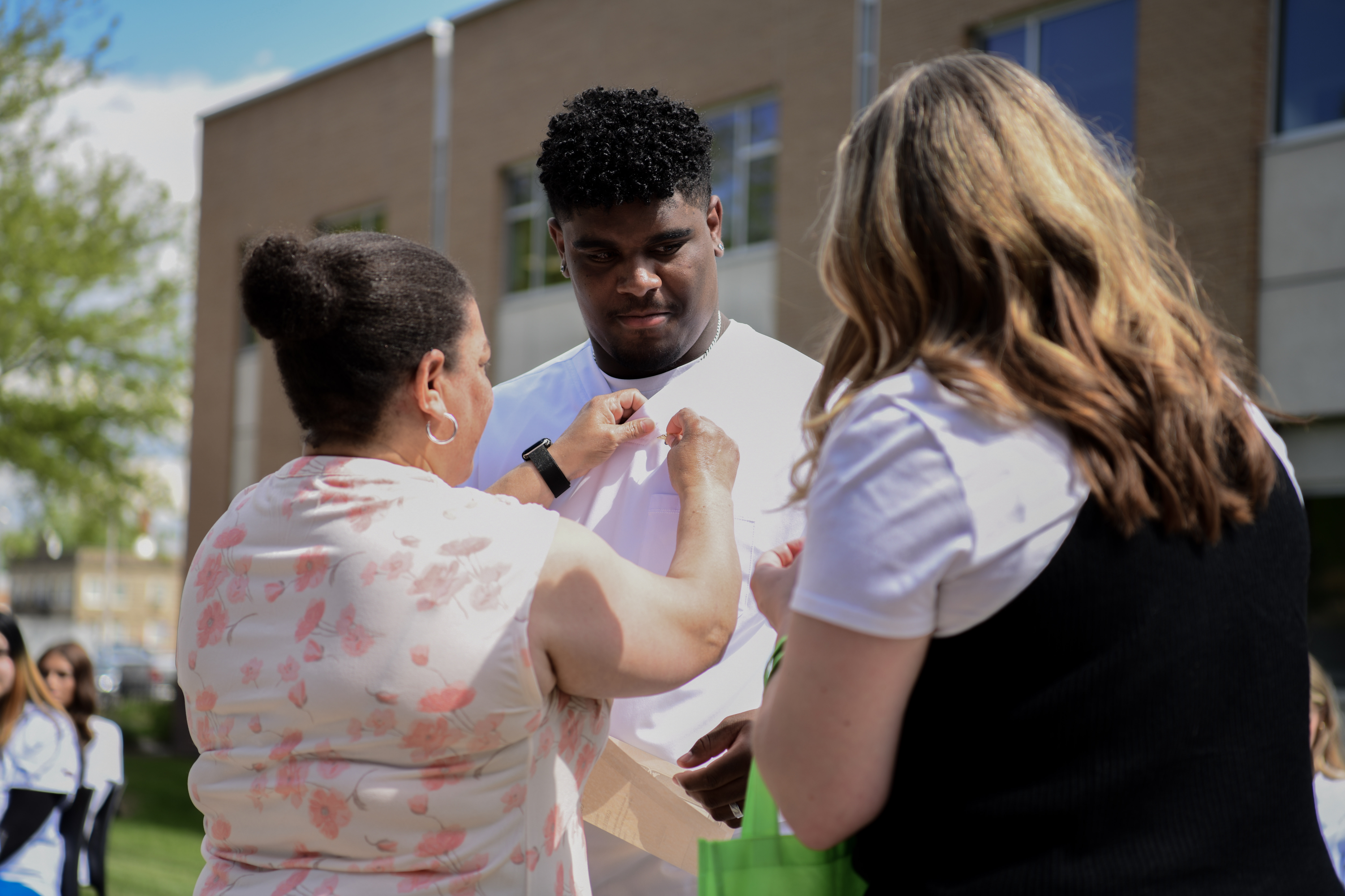 Student receiving pin placed to scrubs uniform