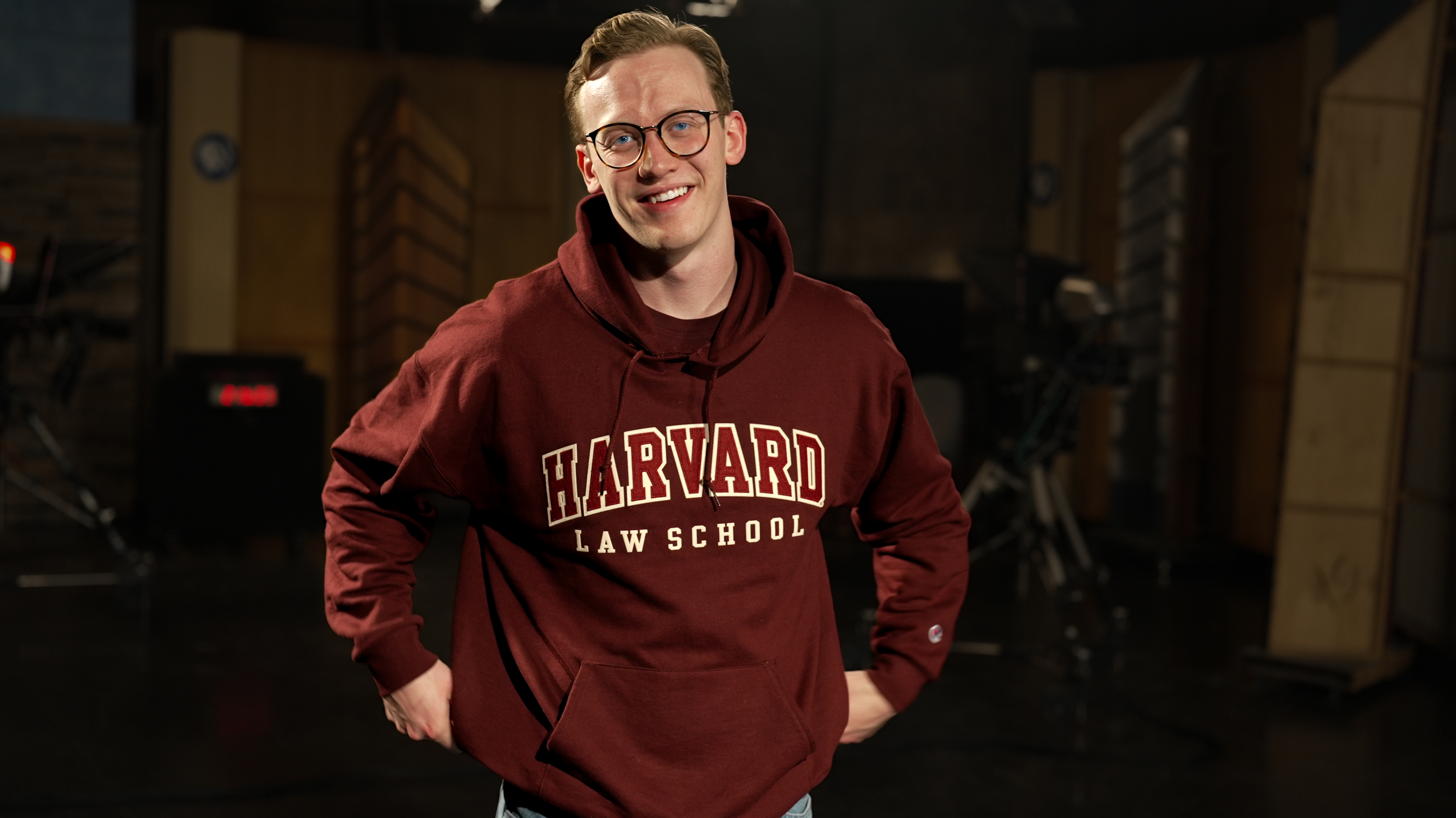 A man wearing a crimson Harvard Law School sweatshirt poses for a photo